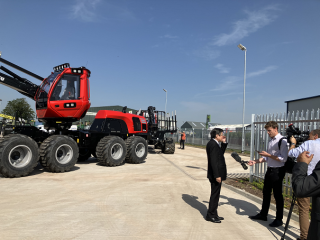 Consul General Fujiwara (middle) being interviewed in front of forestry machinery