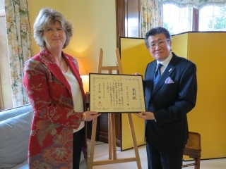 藤原直総領事がサラ・スチュワート氏に表彰を授与する。